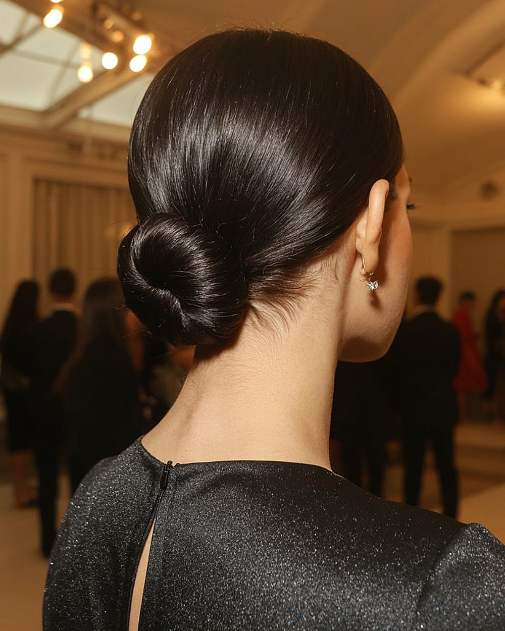 Glossy classic low chignon on sleek black hair, a timeless and easy updo for formal events